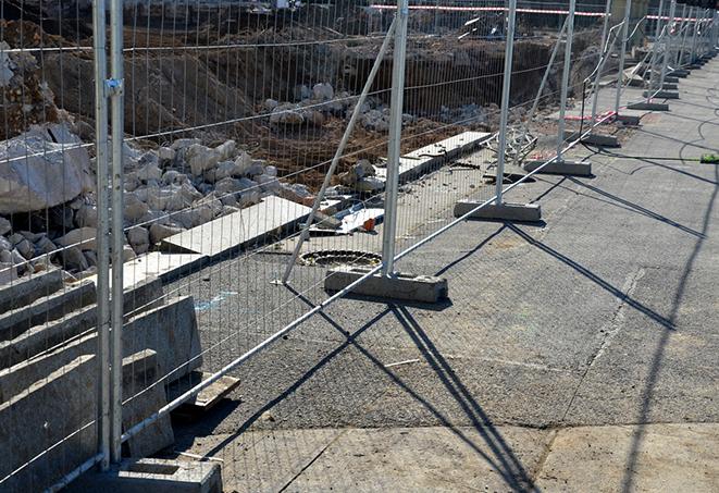 a temporary fence panel gate opening up to a job site with heavy machinery and equipment